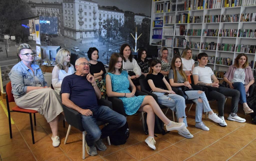 młodzież siedząca w czytelni biblioteki ogląda film